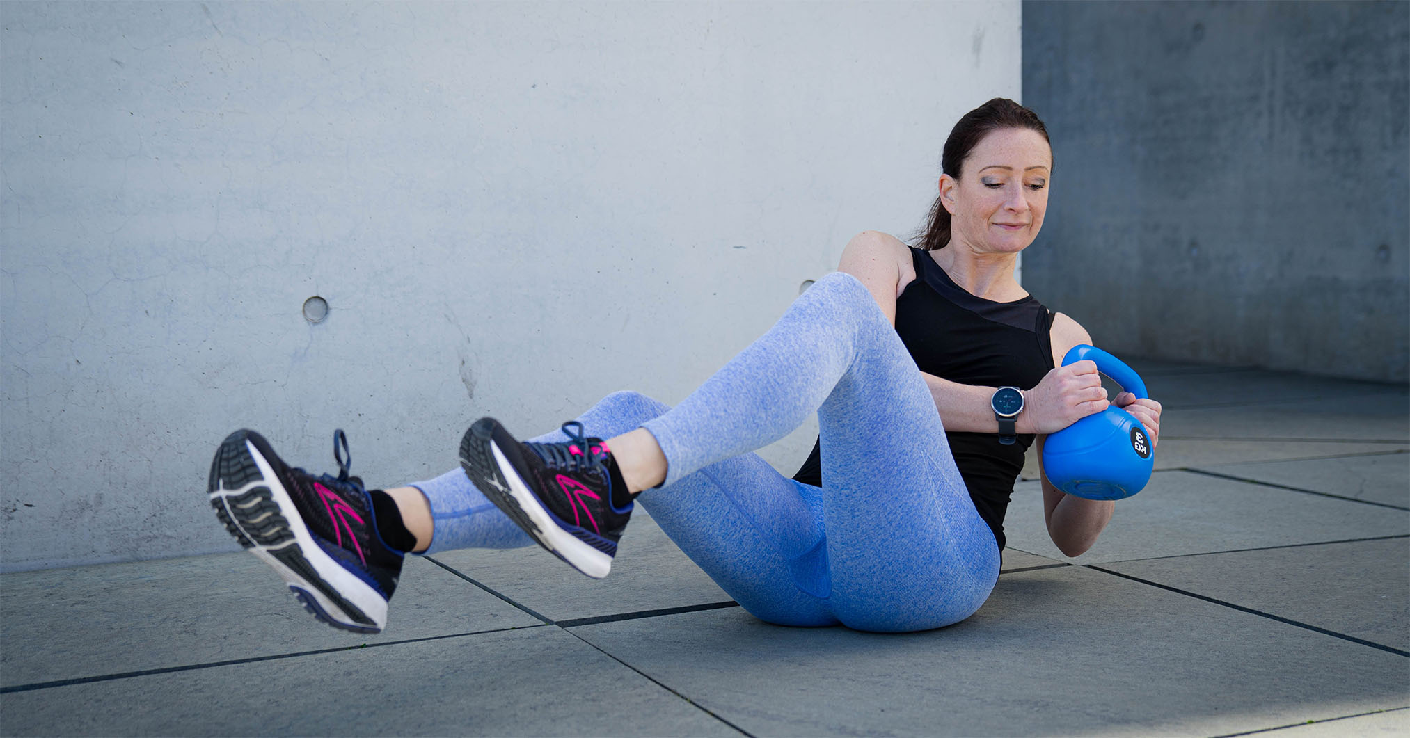 The coach doing a stomach exercise while holding a dumbell.